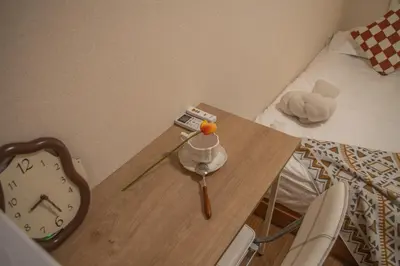 a table with a clock on it next to a bed at Shinjuku 2 stops Higashinakano three people in Tokyo