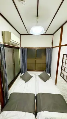 two beds in a small room with windows at \u5d50-\u6c60\u888b4\u5206\u65b0\u5bbf15\u5206 in Tokyo