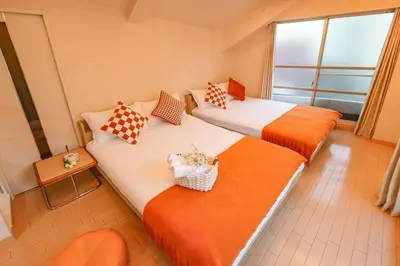 two beds with orange and white sheets in a room at Shinjuku 2 stops 3 bedrooms best groups or family in Tokyo