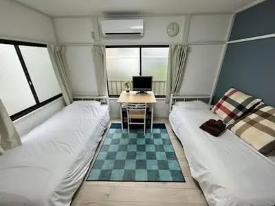 a room with two beds and a desk with a computer at Keiko House in Tokyo