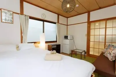 a bedroom with two white beds and a large window at Keiko House in Tokyo