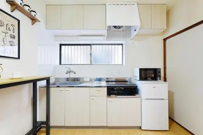 a kitchen with white cabinets and a white refrigerator at Industrial room in Tokyo