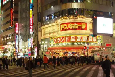 a crowd of people crossing a busy city street at night at \u65b0\u5bbf\u99c5\u307e\u30672\u5206\u65b0\u5927\u4e45\u4fdd\u6238\u5efa\u30663br in Tokyo