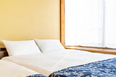 a large bed with white sheets and a window at The Guest House Sakura in Tokyo