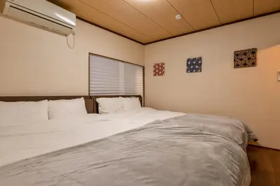 a bedroom with a bed with white sheets and a window at Joyfull House in Tokyo