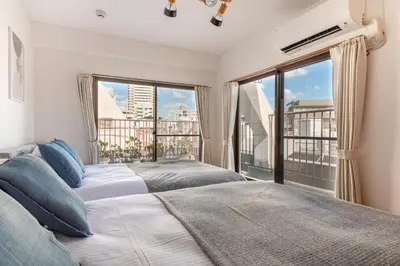 two beds in a bedroom with a large window at Shinjuku Vintage Rooftop Terrace Stay in Tokyo