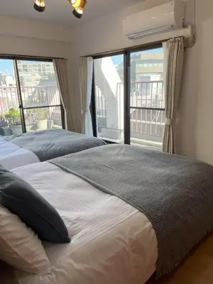 two beds in a bedroom with a large window at Shinjuku Vintage Rooftop Terrace Stay in Tokyo