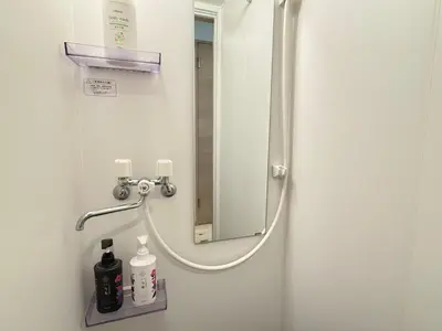 a shower in a hospital bathroom with a mirror at Shinjuku Cloudlive AH in Tokyo