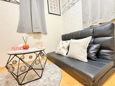 a black leather couch with a side table in a living room at Shinjuku Cloudlive AH in Tokyo