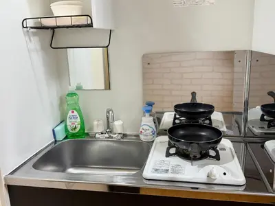 a kitchen with a sink and a frying pan on a stove at Shinjuku Cloudlive AH in Tokyo