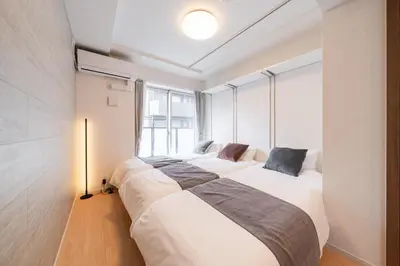 two beds in a room with a large window at Terrace Tokyo Otsuka South in Tokyo