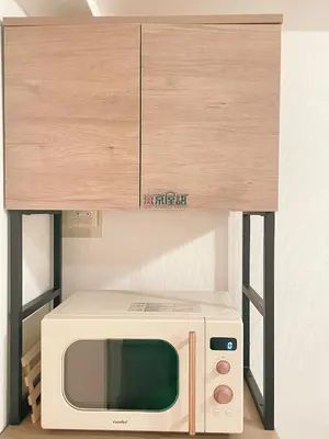 a microwave oven sitting under a wooden cabinet at Home Story in Tokyo KANAMETYOU&Ikebukuro-Ginnzaまで直通&東京屋語 in Tokyo