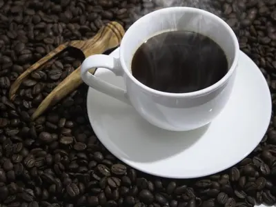 a cup of coffee on top of coffee beans at eeGee STAY Kamata