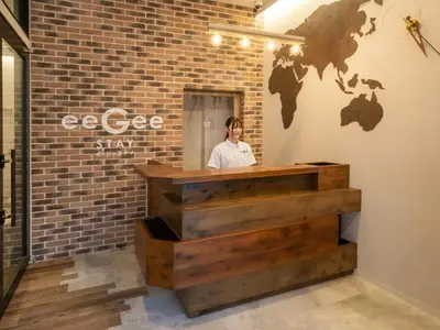 a woman standing behind a counter in a brick wall at eeGee STAY Kamata