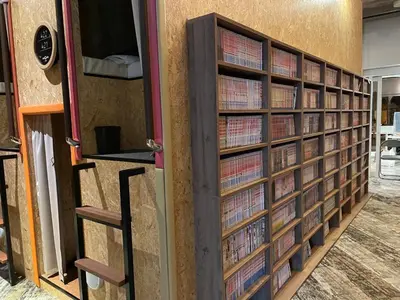 a wall of book shelves filled with books at eeGee STAY Kamata