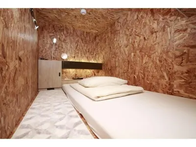 a bed in a room with a wooden wall at eeGee STAY Kamata