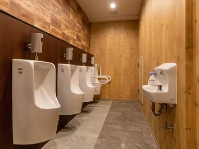a bathroom with a row of urinals and a sink at eeGee STAY Kamata