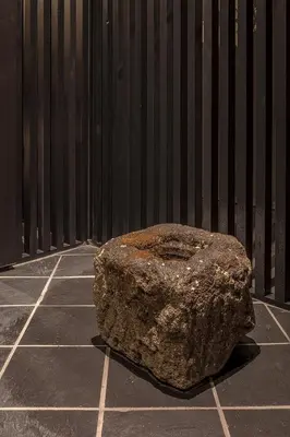a large rock sitting on a sidewalk next to a wall at ENSO TOKYO Akasaka in Tokyo