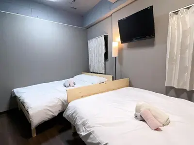 two beds in a room with a tv on the wall at TD Link Ooyama Cozy Escape Sleeps 8 Direct to Ikebukuro in Tokyo