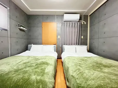 two beds in a small room with green sheets at Amika First 101 AF11 in Tokyo