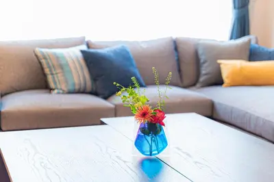 a blue vase with flowers on a table in front of a couch at Poka Villa Aoyama in Tokyo