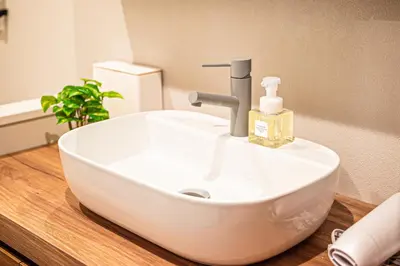 a white bathroom sink with a soap dispenser on it at Poka Villa Aoyama in Tokyo