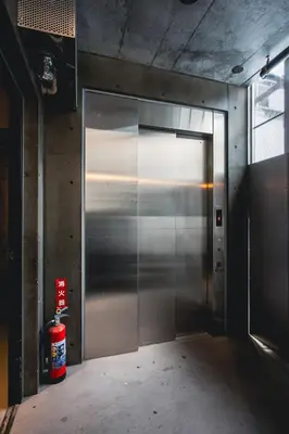 a metal elevator door in a building with a fire extinguisher at Rimba Tokyo Oshiage, Skytree view, 3BR 80m2 in Tokyo