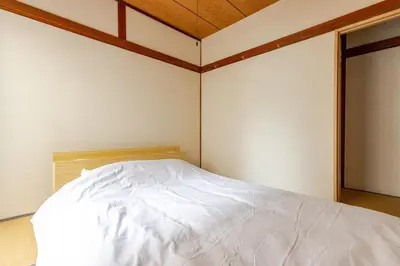 a white bed in a room with a wooden ceiling at Flower House in Tokyo