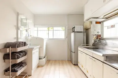 a kitchen with white cabinets and a refrigerator at Flower House in Tokyo