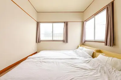 a white bed in a room with two windows at Flower House in Tokyo