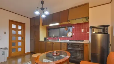 a kitchen with a table and a stainless steel refrigerator at Momiji Hotel in Tokyo