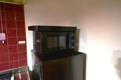 a microwave on top of a refrigerator in a kitchen at Momiji Hotel in Tokyo