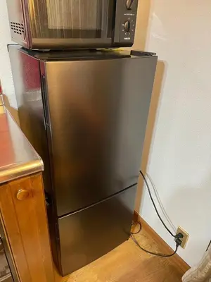 a stainless steel refrigerator with a microwave on top of it at Momiji Hotel in Tokyo