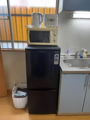 a microwave on top of a refrigerator in a kitchen at Yellow House in Tokyo