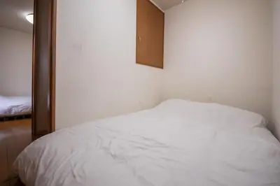 a small bedroom with a white bed and a cabinet at Yellow House in Tokyo