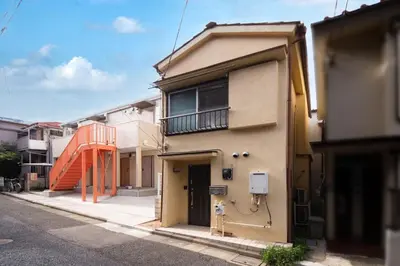a building with an orange staircase on the side of it at Yellow House in Tokyo