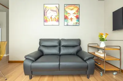 a leather couch in a living room with three paintings at Home suite Home Ryogoku - Perfect for Families and Groups, Spacious 197m2 Home with 8 BR & 3 BA, Up to 15 ppl with Parking and 3 Stations in Tokyo