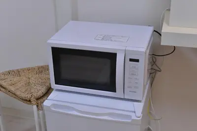 a white microwave sitting on top of a chair at \u30b5\u30f3\u30ef\u30a4\u30c9\u9ad8\u6a4b\u30d3\u30eb in Tokyo