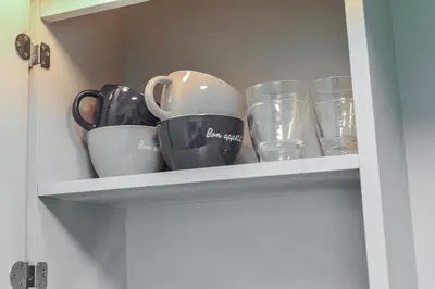 a cupboard with cups and dishes on it at \u30b5\u30f3\u30ef\u30a4\u30c9\u9ad8\u6a4b\u30d3\u30eb in Tokyo