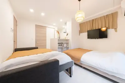 two beds in a bedroom with a tv on the wall at House hotel EKODA 101 HE11 in Tokyo