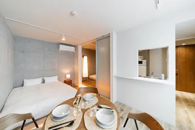 a bedroom with a bed and a table with chairs at Tabiya Shinamachi - New built APT at Ikebukuro, Relaxing Stay in Central Tokyo in Tokyo