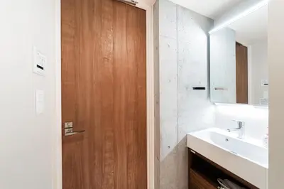 a bathroom with a sink and a wooden door at Tabiya Shinamachi - New built APT at Ikebukuro, Relaxing Stay in Central Tokyo in Tokyo