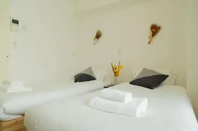 two white beds with black pillows in a room at Ikebukuro 302 - Twin Room in Tokyo