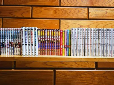 a row of books on a wooden book shelf at \u5927\u5c71\u6c11\u6cca \u6f2b\u753b\u5c0f\u5c4b \u6700\u59278\u4eba \u8907\u5f0f2\u5c64 \u6c60\u888b\u96fb\u8eca 5\u5206 in Tokyo