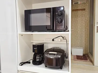 a microwave and a coffee maker on a shelf at \u5927\u5c71\u6c11\u6cca \u6f2b\u753b\u5c0f\u5c4b \u6700\u59278\u4eba \u8907\u5f0f2\u5c64 \u6c60\u888b\u96fb\u8eca 5\u5206 in Tokyo