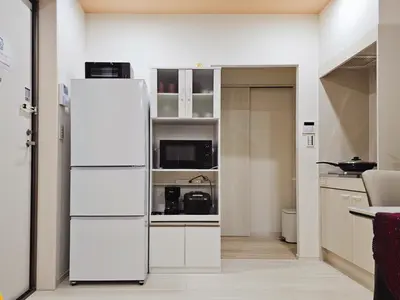a kitchen with a white refrigerator in a room at \u5927\u5c71\u6c11\u6cca \u6f2b\u753b\u5c0f\u5c4b \u6700\u59278\u4eba \u8907\u5f0f2\u5c64 \u6c60\u888b\u96fb\u8eca 5\u5206 in Tokyo