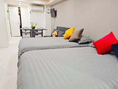 two beds in a room with a dog sitting between them at \u5927\u5c71\u99c5\u5f92\u6b698\u5206 \u6c60\u888b\u307e\u3067\u96fb\u8eca\u30675\u5206 \u6700\u59276\u4eba\u5bbf\u6cca in Tokyo