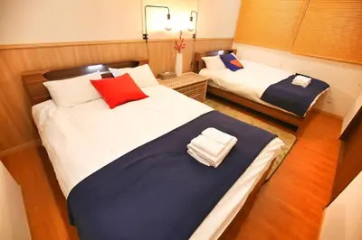 two beds in a small room with at \u5fa1\u4eac\u30db\u30c6\u30eb in Tokyo