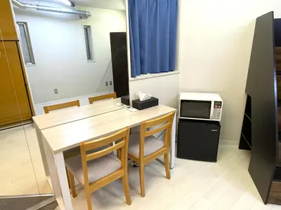 a room with a table and chairs and a microwave at Hot Deal! Simple, no-frills room 3 guest in Tokyo