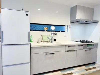 a kitchen with white cabinets and a refrigerator at Hao Bros Home Gemini in Tokyo